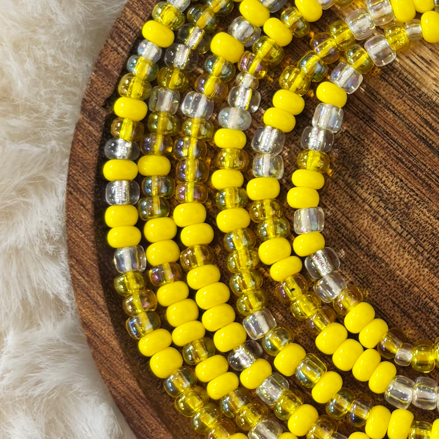 Handcrafted waist bead strand featuring bright lemon-yellow seed beads mixed with translucent golden and clear glass accents, created by Waisted by Design.