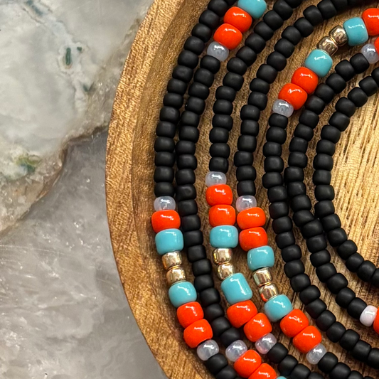 Fierce Flame waist beads with matte black seed beads and coral-red, turquoise, and gold accent beads in a bold pattern.