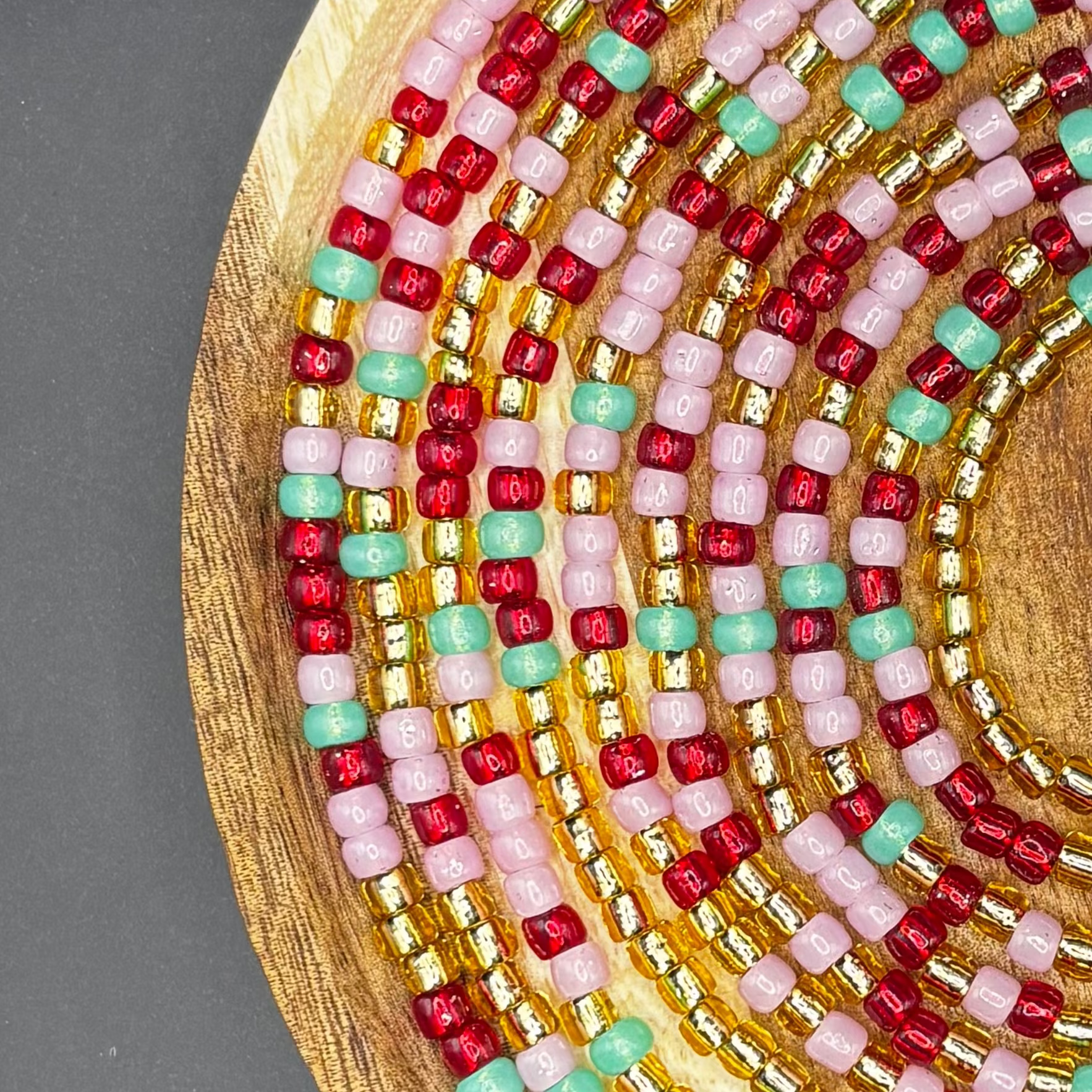 Handmade strawberry, light green and red pink waist beads with soft feminine tones designed for body adornment and self-love.